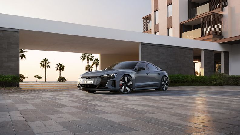 Vue latérale d'une Audi e-tron GT quattro devant un bâtiment moderne.