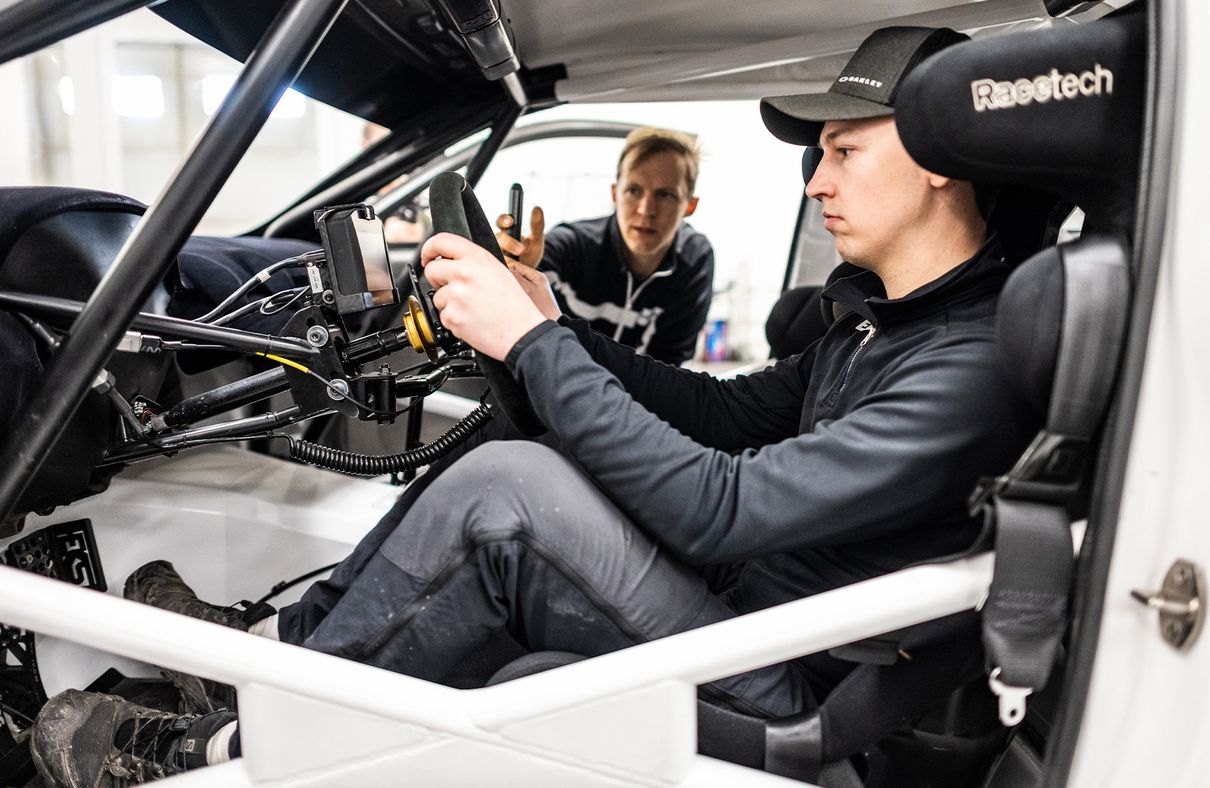 Emil Bergkvist achter het stuur van de Audi RS Q e-tron. Op de achtergrond is Mattias Ekström te zien.
