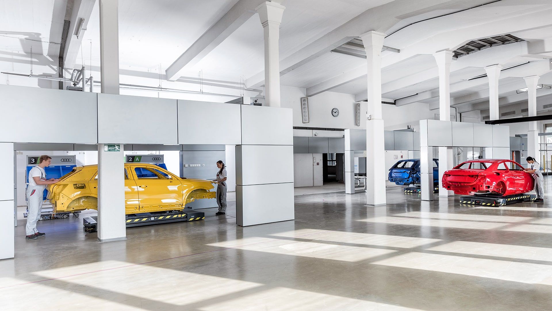Das Bild zeigt eine moderne Produktionshalle mit Audi Karosserien auf fahrerlosen Transportsystemen.