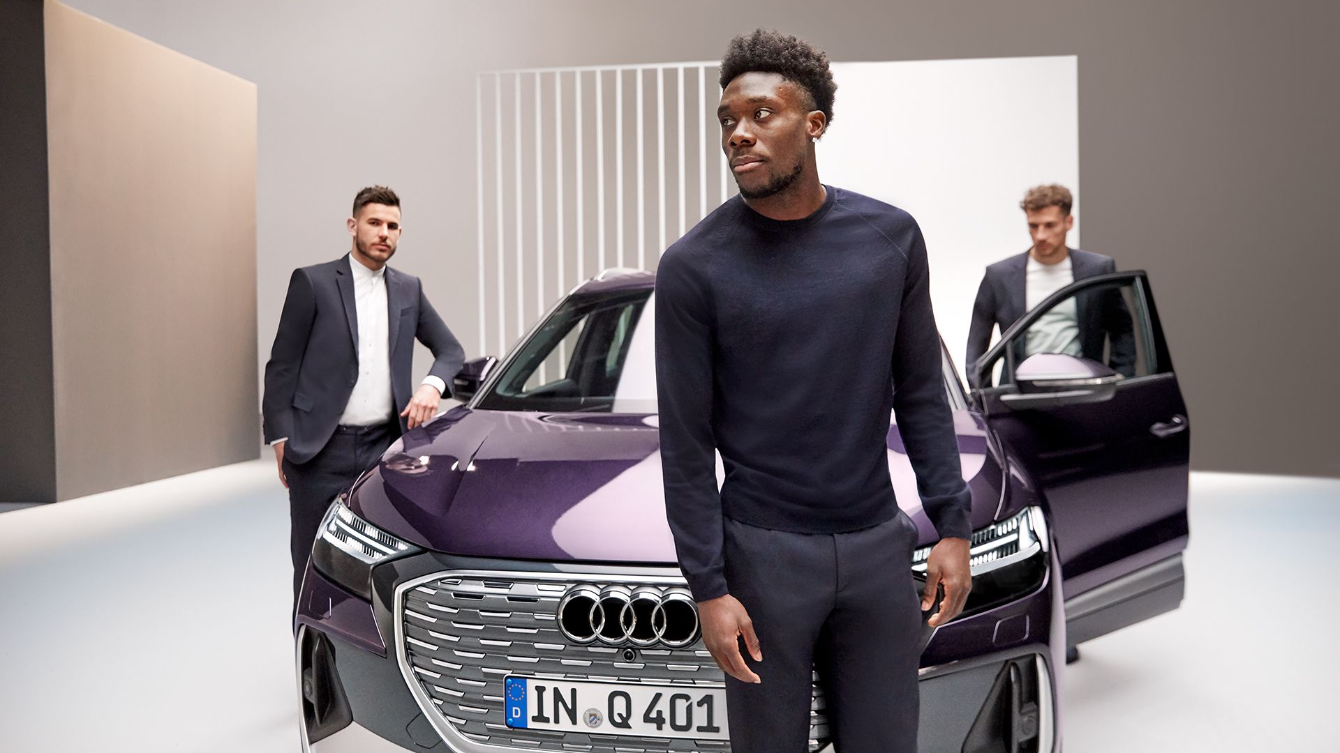 Bayern Munich players Lucas Hernández, Alphonso Davies and Leon Goretzka (from left) and the Audi Q4 e-tron. 