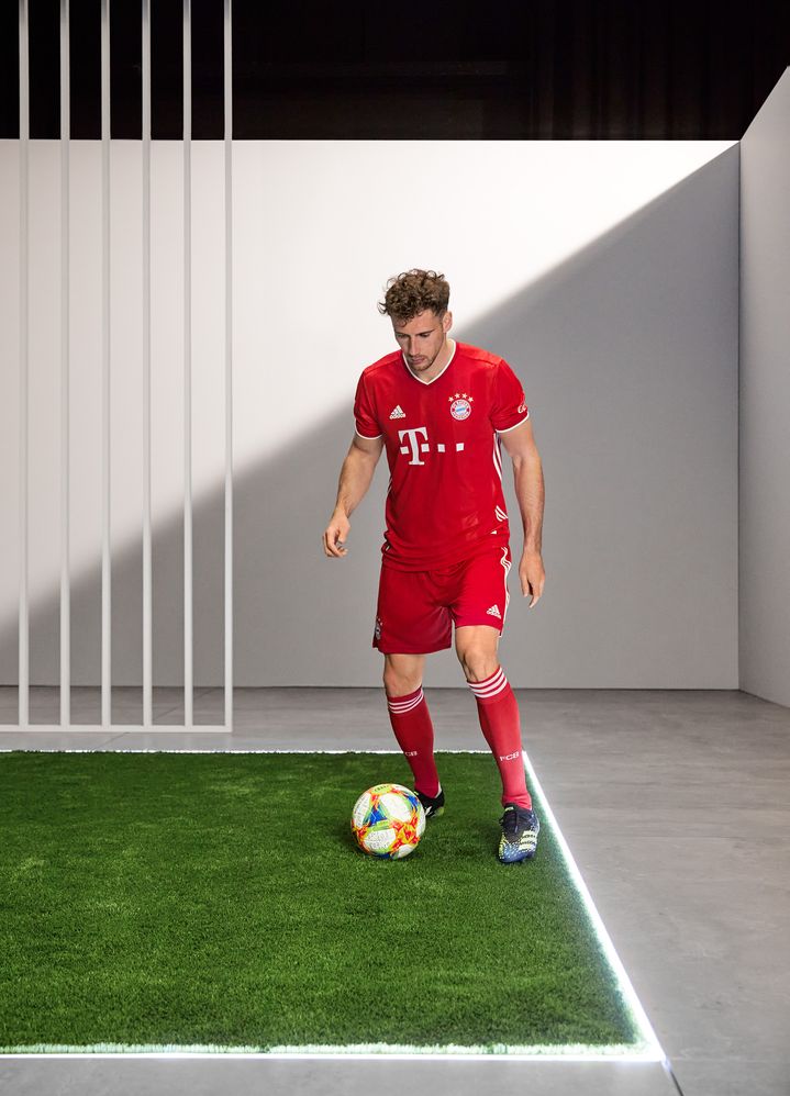 Leon Christoph Goretzka, joueur du Bayern Munich, tape dans un ballon de foot sur un morceau de pelouse installé dans le studio. 