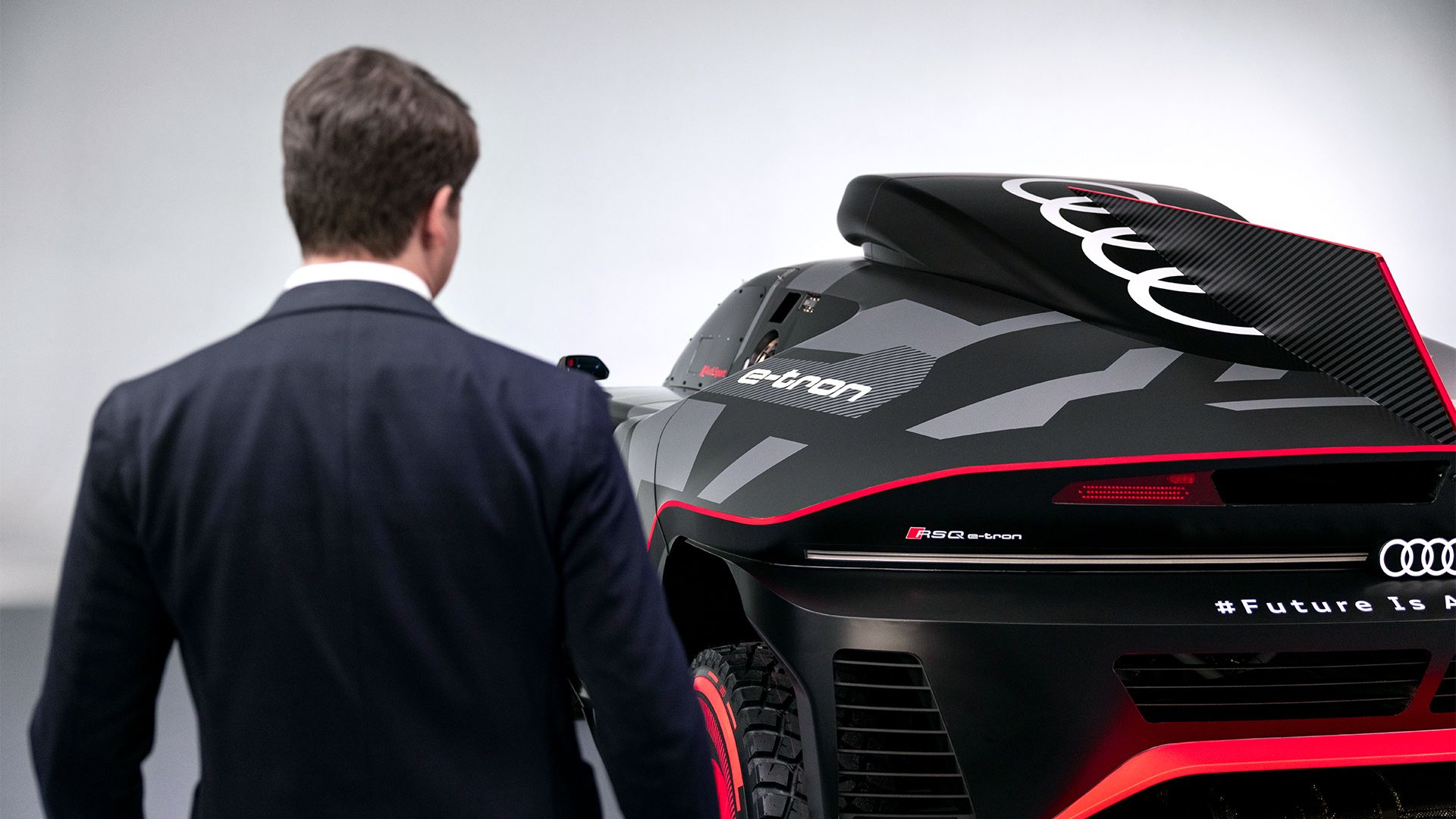 Julius Seebach standing with his back to the camera, to the left of the Audi RS Q e-tron.