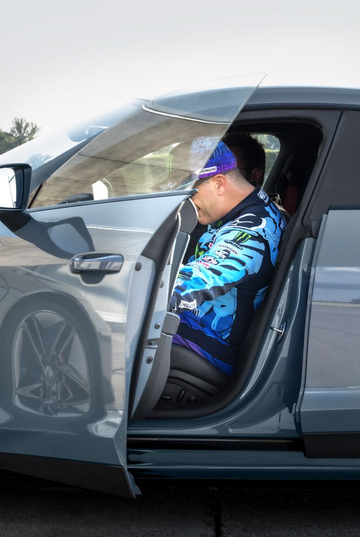 Ken Block is sitting in the car and is just about to close the door.