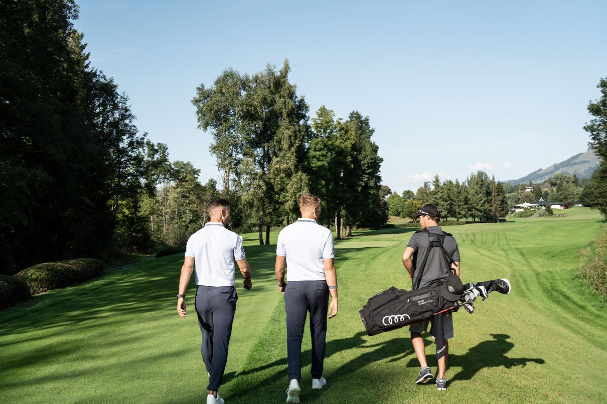 De golftrainers Piers Ward en Andy Proudman lopen met een van hun leerlingen over de baan.