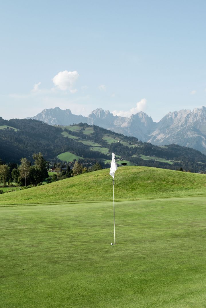 The Kitzbühel golf course’s green hills with mountains as a backdrop.