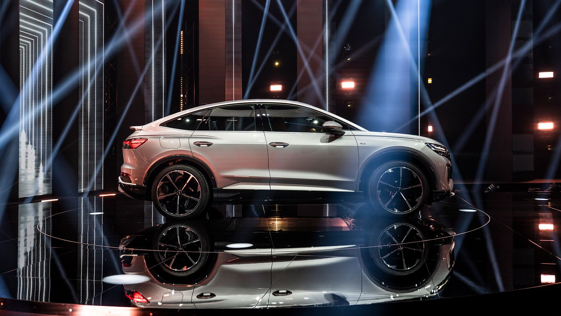 Eine Seitenaufnahme eines silberfarbenen Audi Q4 Sportback e-tron auf der Bühne.