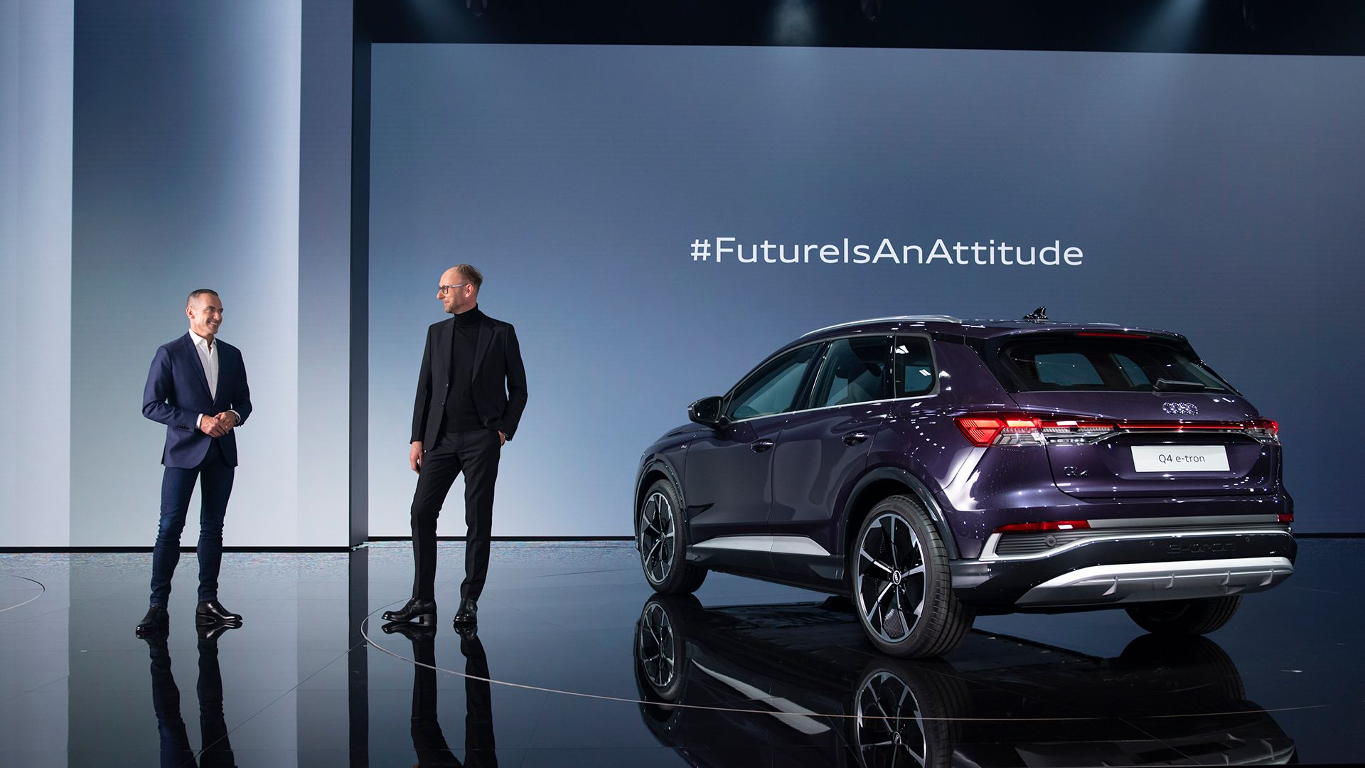 Henrik Wenders and Marc Lichte stand on the stage with the purple Audi Q4 e-tron. 