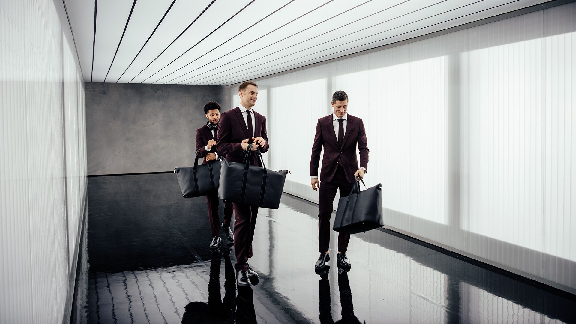 Dressed in lounge suits, the three professional footballers stride down a passageway.