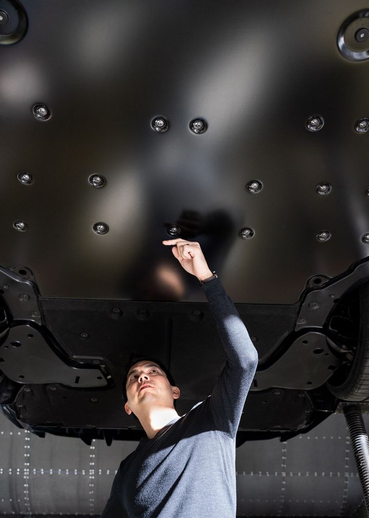 Dr. Kentaro Zens, verantwortlicher Aerodynamiker des Audi RS e-tron GT, zeigt auf den  Unterboden des Sportwagens. 