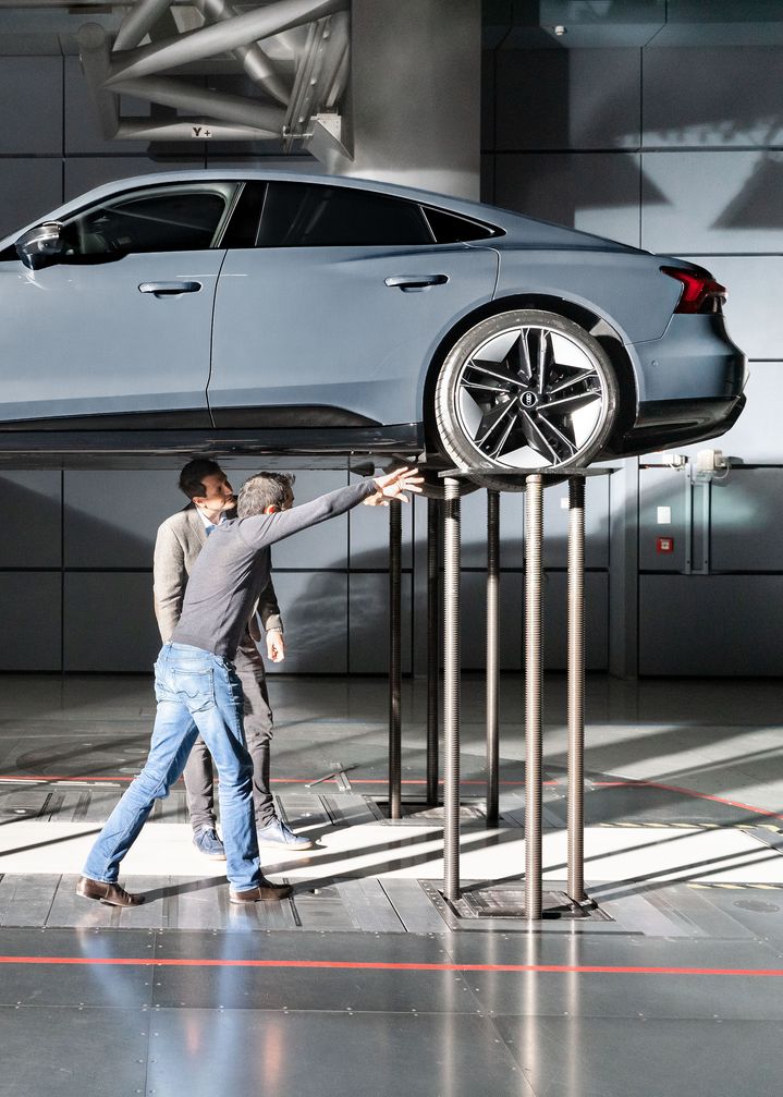 Thomas Redenbach und Kentaro Zens stehen unter dem angehobenen Audi RS e-tron GT und diskutieren. 