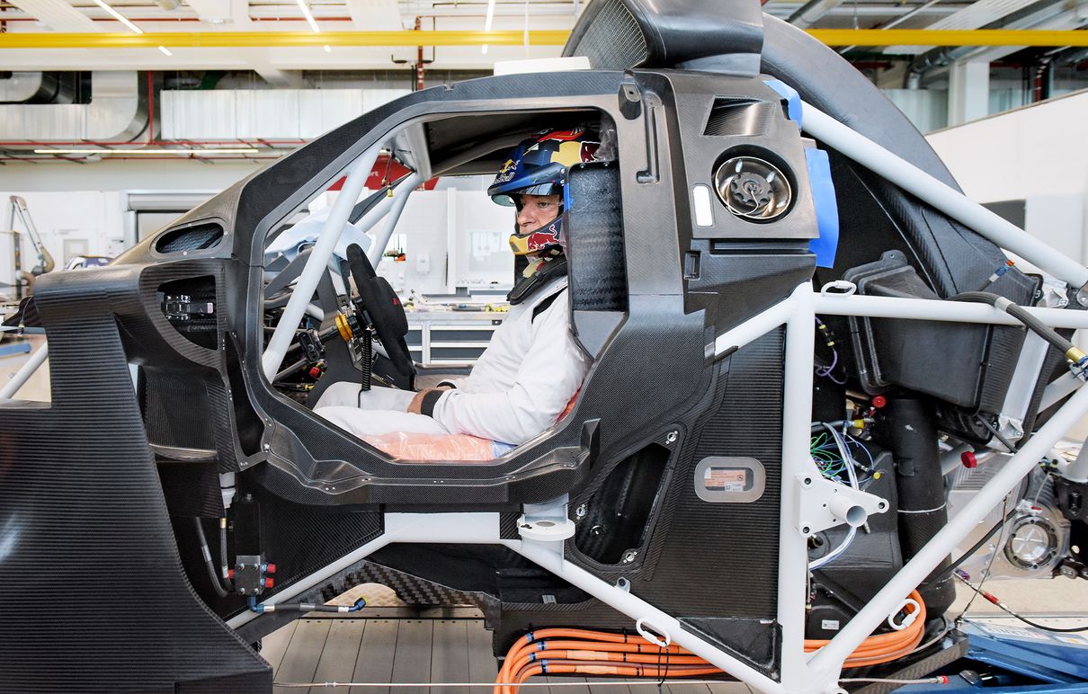 Audi Sport’un Dakar Ralli pilotlarından biri olan Carlos Sainz, ralli otomobilinin iskeletinde, kendisine uygun koltuk haline gelecek kalıp üzerinde oturuyor. Direksiyonun arkasında turuncu bir köpük minder üzerinde oturuyor. 