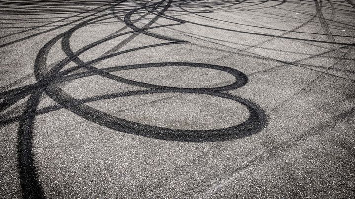 Des traces de pneus circulaires sont visibles sur l'asphalte. 