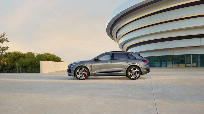 Zijaanzicht van de Audi Q8 e-tron voor een futuristisch gebouw