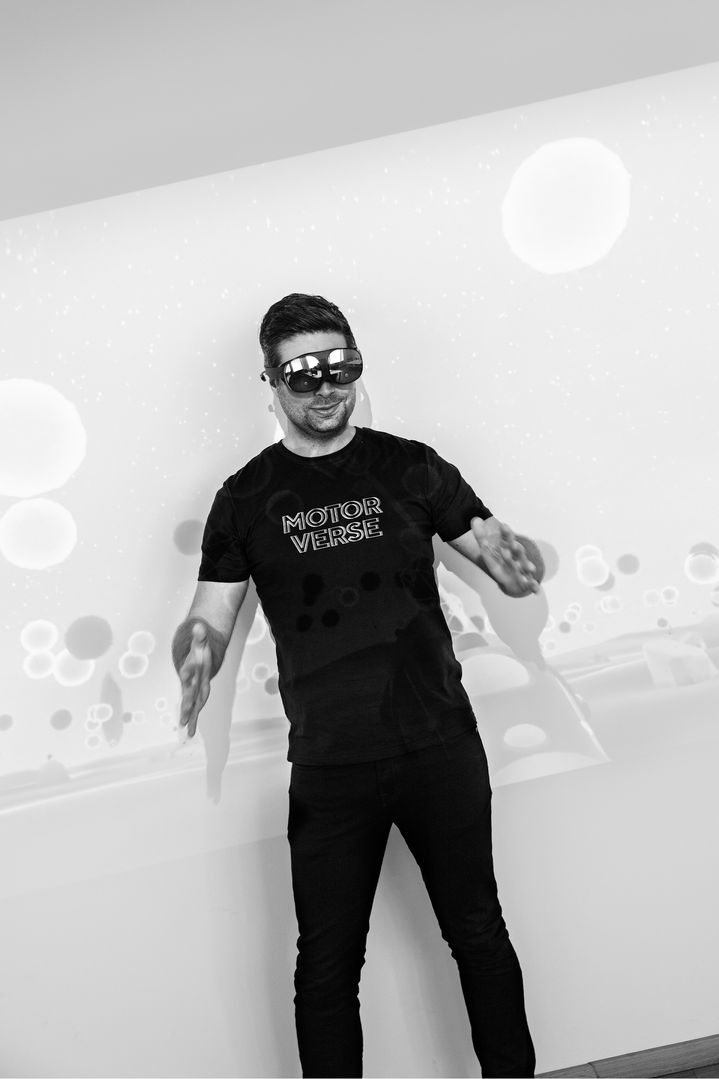 Nils Wollny trägt eine VR-Brille und bewegt sich im Büro vor einer Projektion eines Spiels.