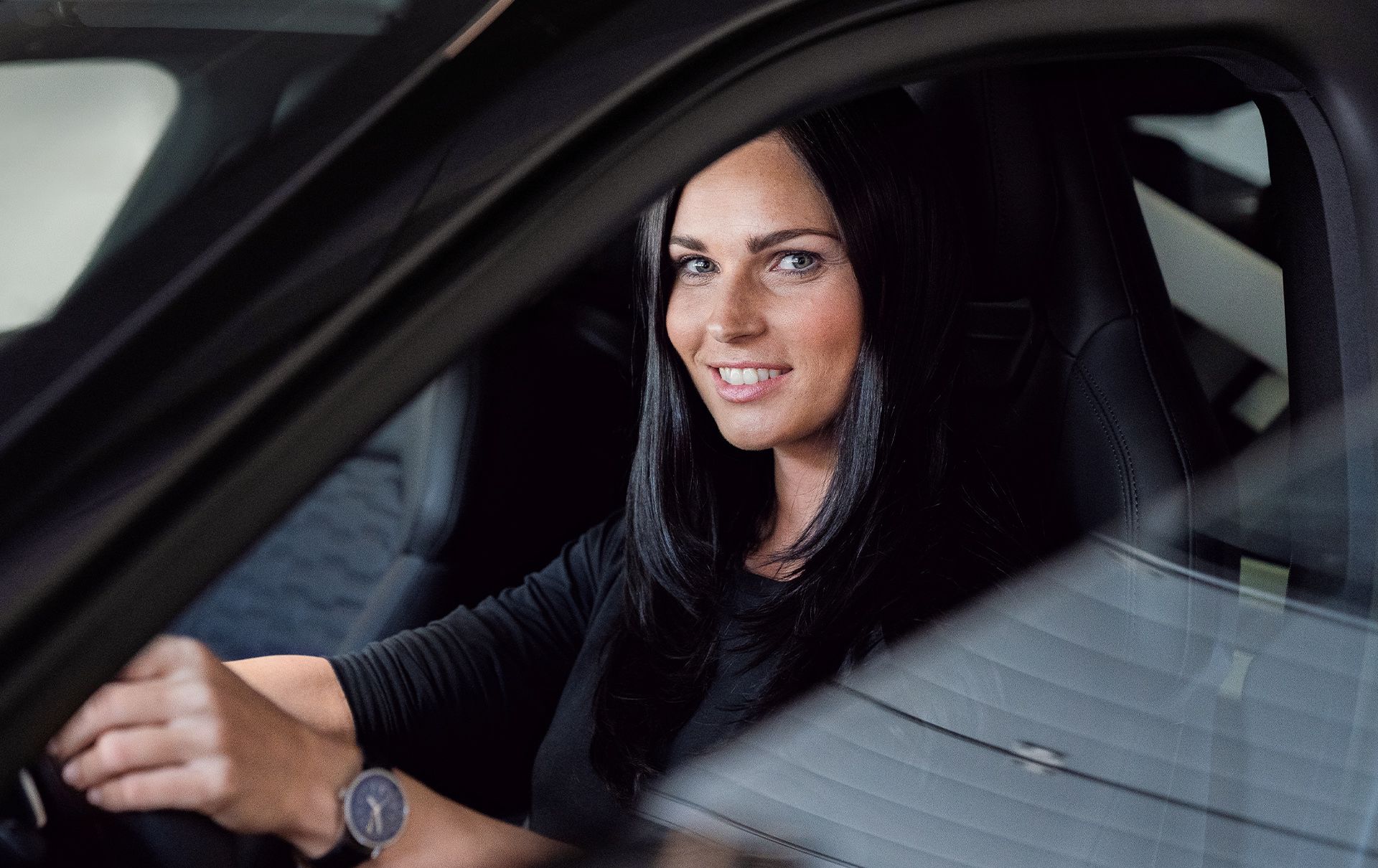 Anna Veith sits at the steering wheel in the Audi e-tron GT and looks into the camera.