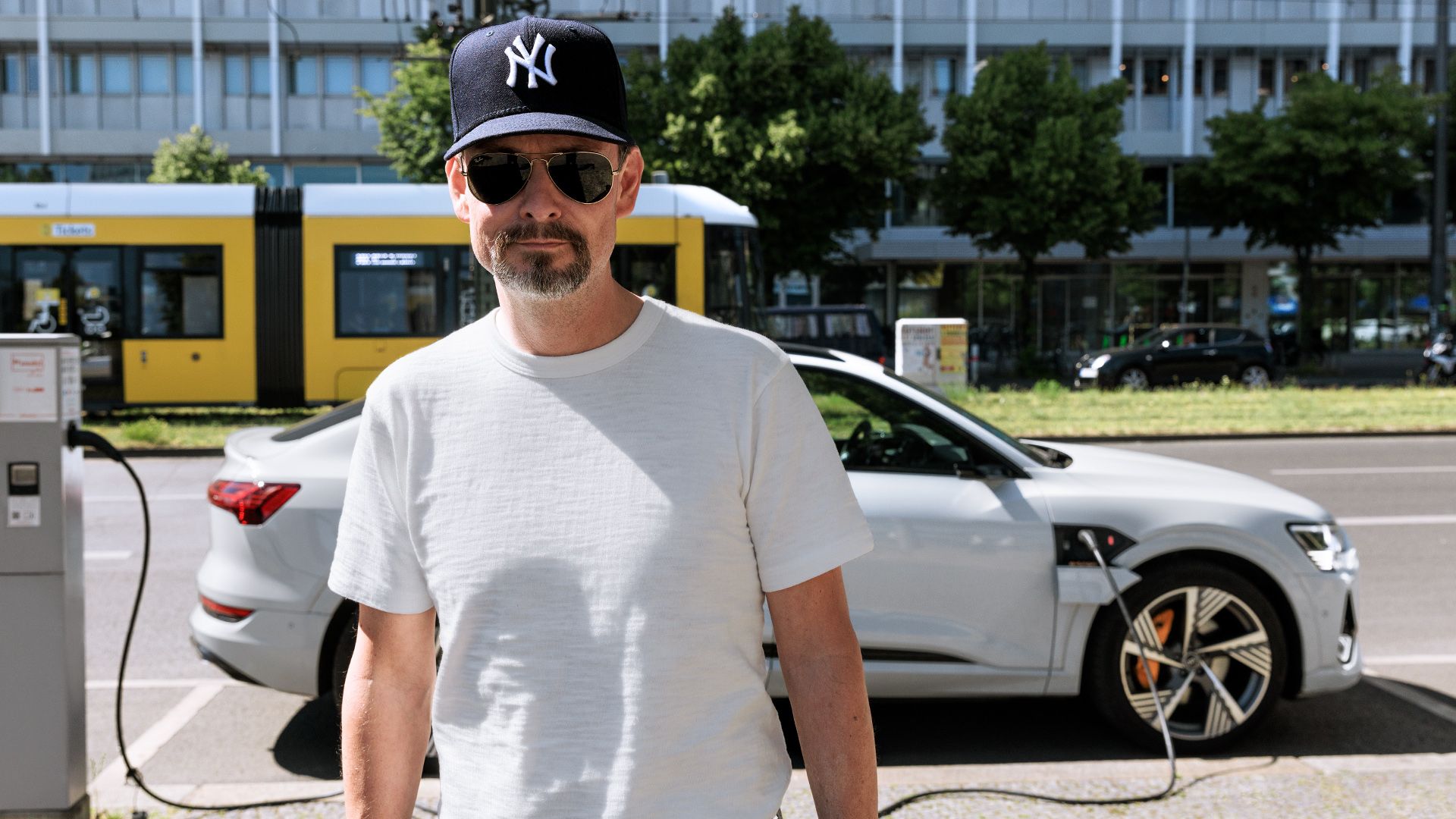 Marco Voigt connects his white Audi e-tron Sportback to a charging station in the city of Berlin.