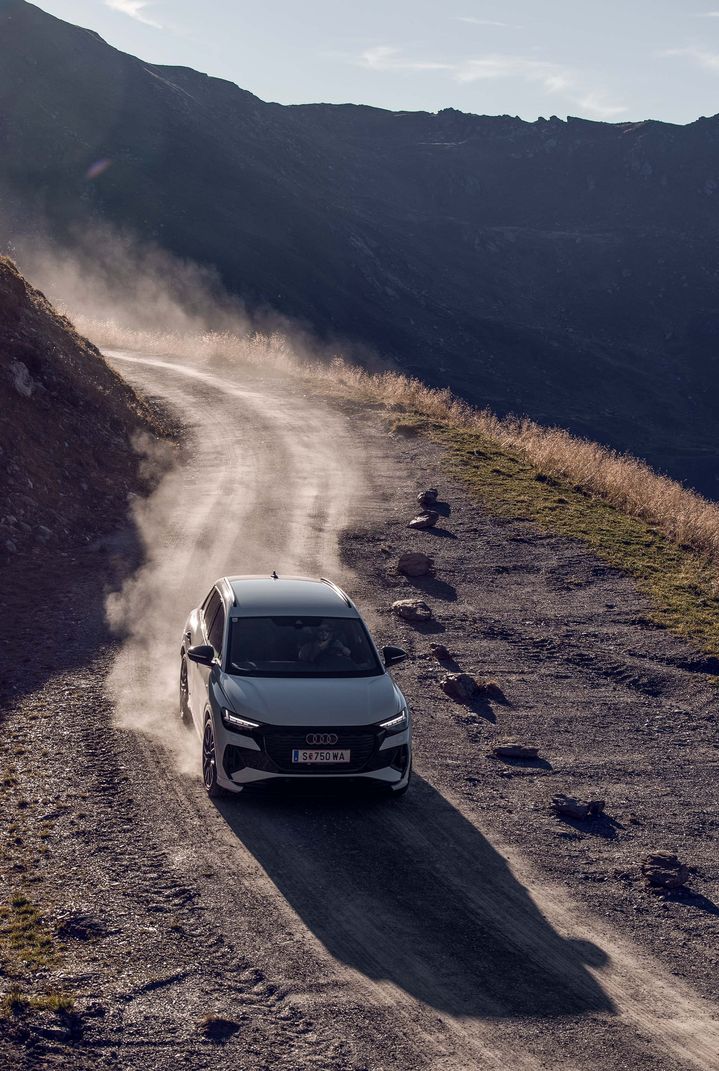 Une Audi Q4 e-tron blanche descend une route de montagne.