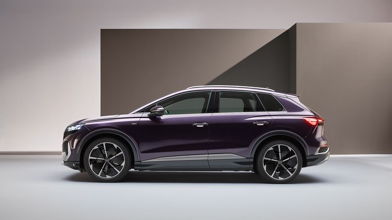 A purple Audi Q4 e-tron stands in front of a wall.