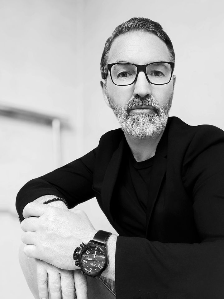 Een zwart-wit-portret van designer Rafael Falkenburger, die in de camera kijkt.