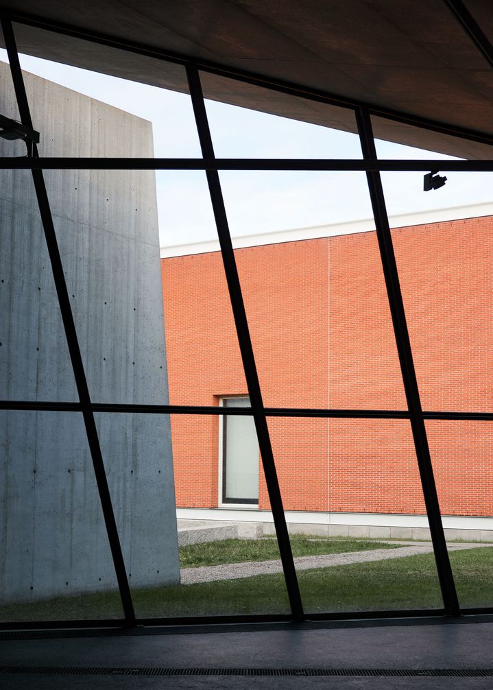 Vista attraverso una facciata di vetro su un edificio di mattoni.