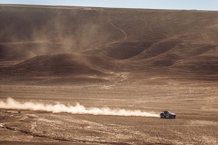 The Audi RS Q e-tron drives through the desert, trailing a cloud of dust