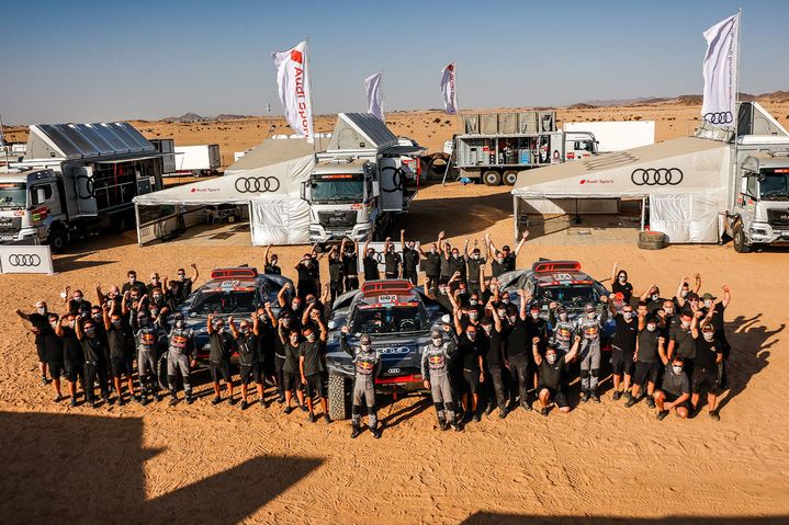 Group photo of the Audi Sport Dakar Rally team in the paddock