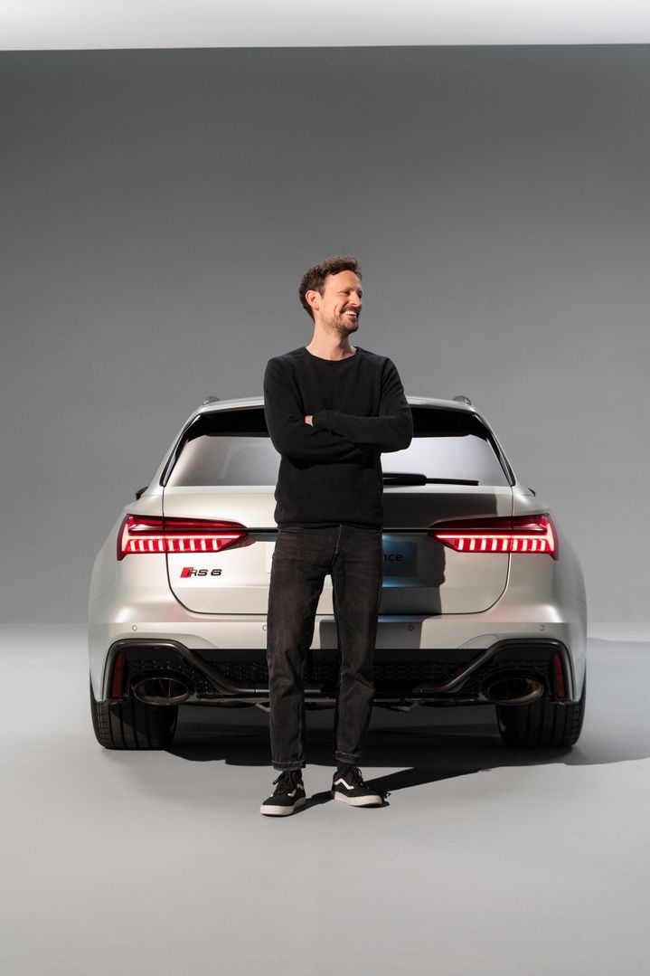 Markus Eberle standing in front of the rear of the Audi RS 6 Avant performance with a smile on his face.
