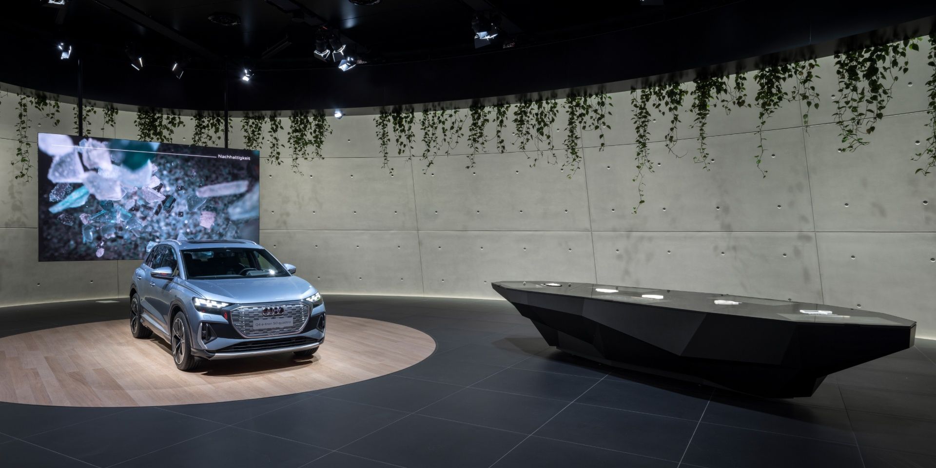 Si vedono Audi Q4 e-tron e una proiezione sul tema della sostenibilità. Lì accanto c'è il tavolo informativo.