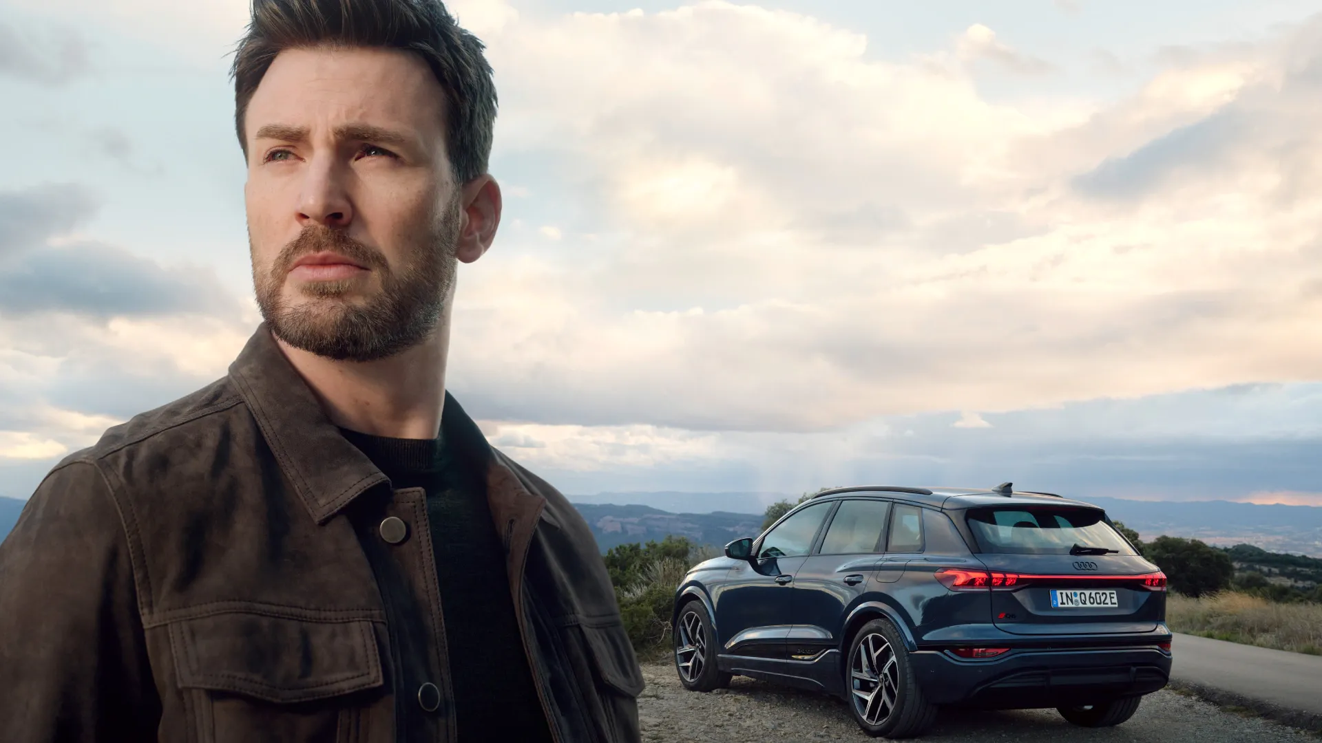 Chris Evans is standing close to the camera with the Audi Q6 e-tron in the background.