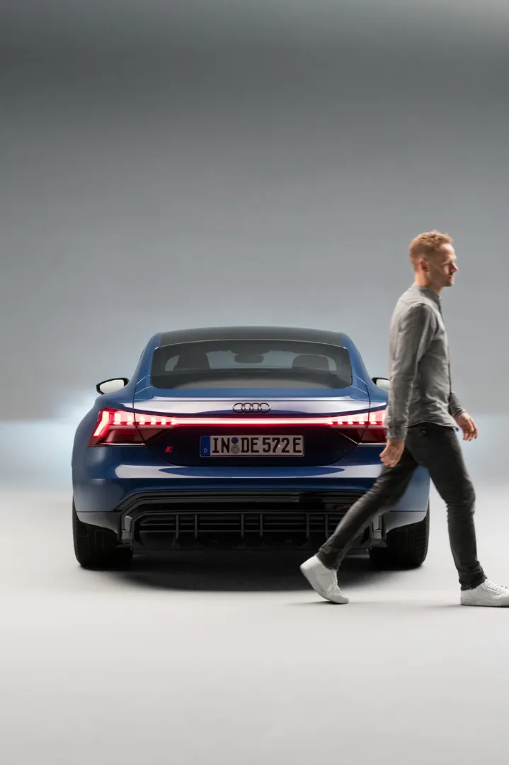 Christopher walking out of the picture alongside the rear of the Audi RS e-tron GT.